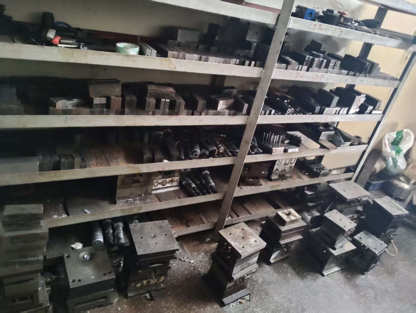 Shelving stacked with steel mould bases and tooling components for zinc-alloy die-casting