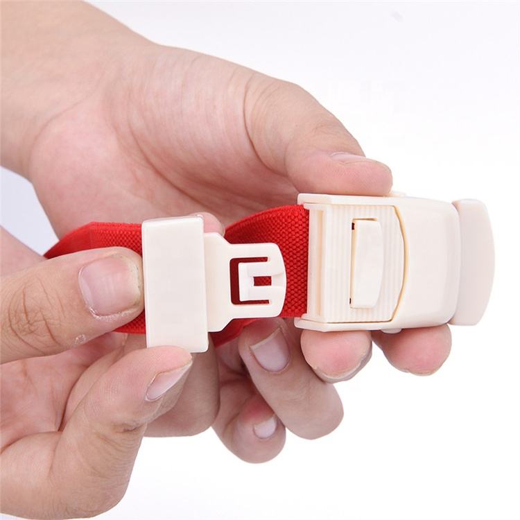 Hand demonstrating the buckle mechanism on a red tourniquet strap