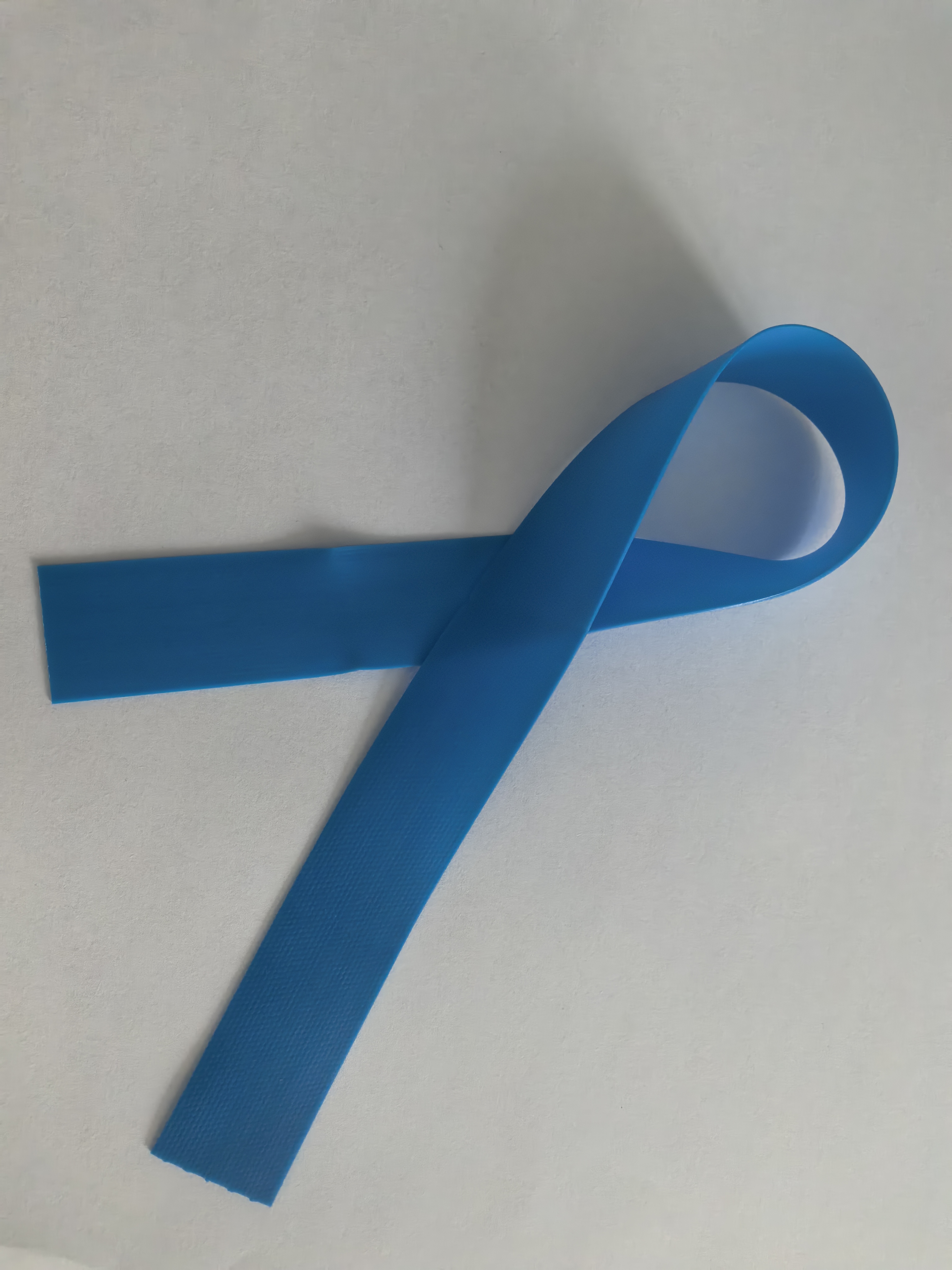 Blue disposable tourniquet strip looped on a neutral inspection surface