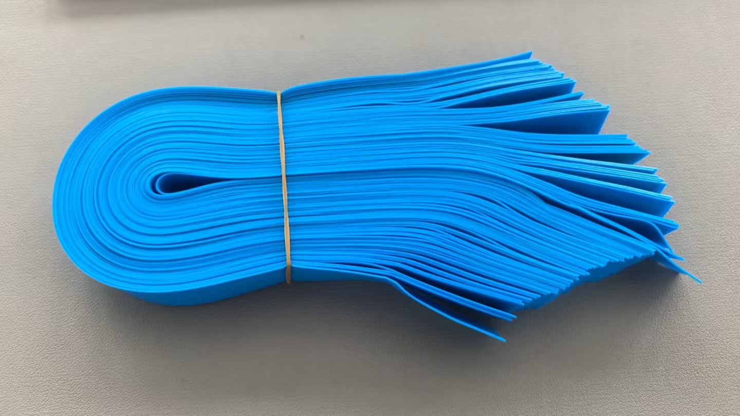 Bulk bundle of blue disposable tourniquet strips on an inspection surface