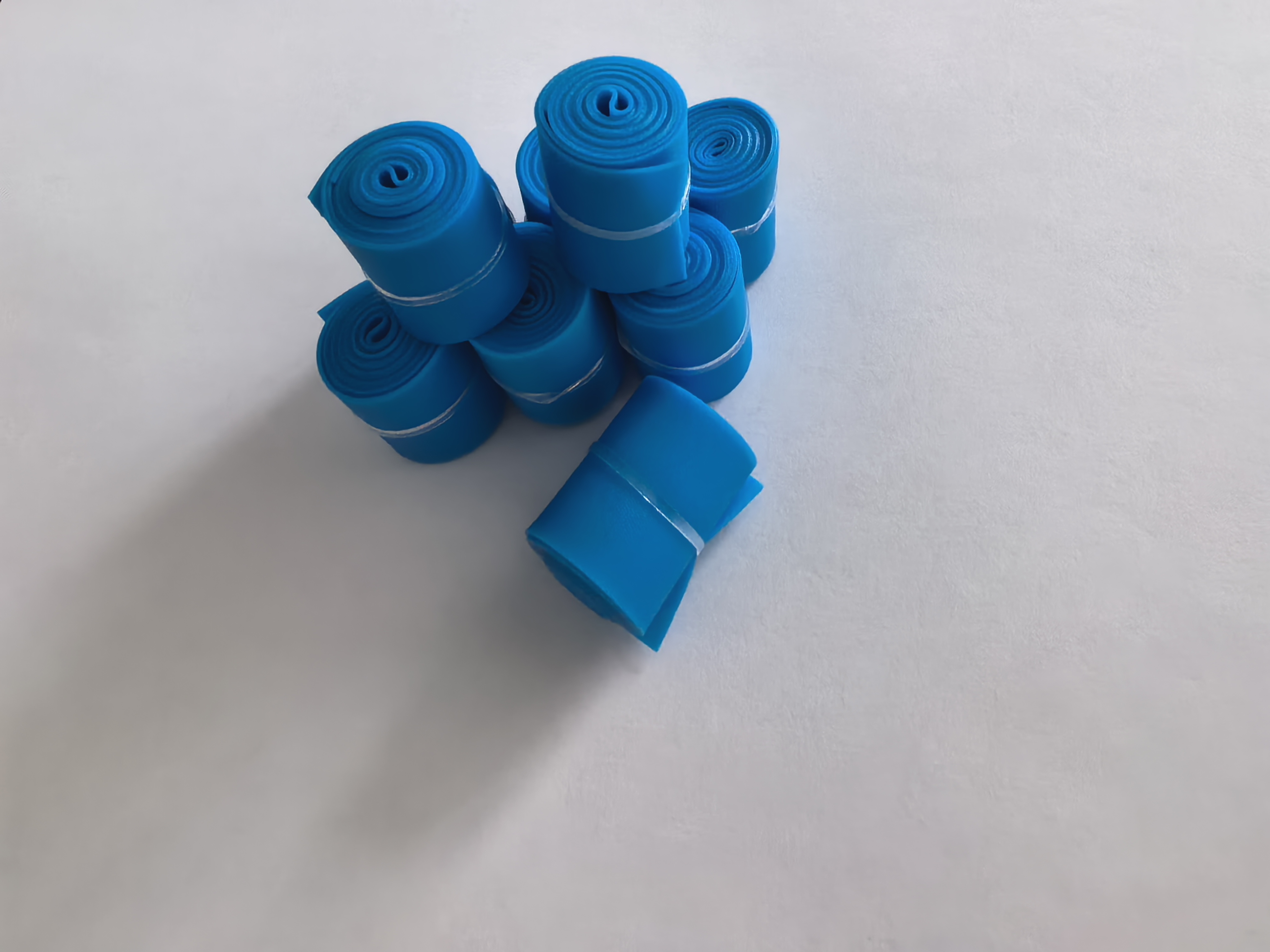 Group of rolled blue disposable tourniquet strips on an inspection surface