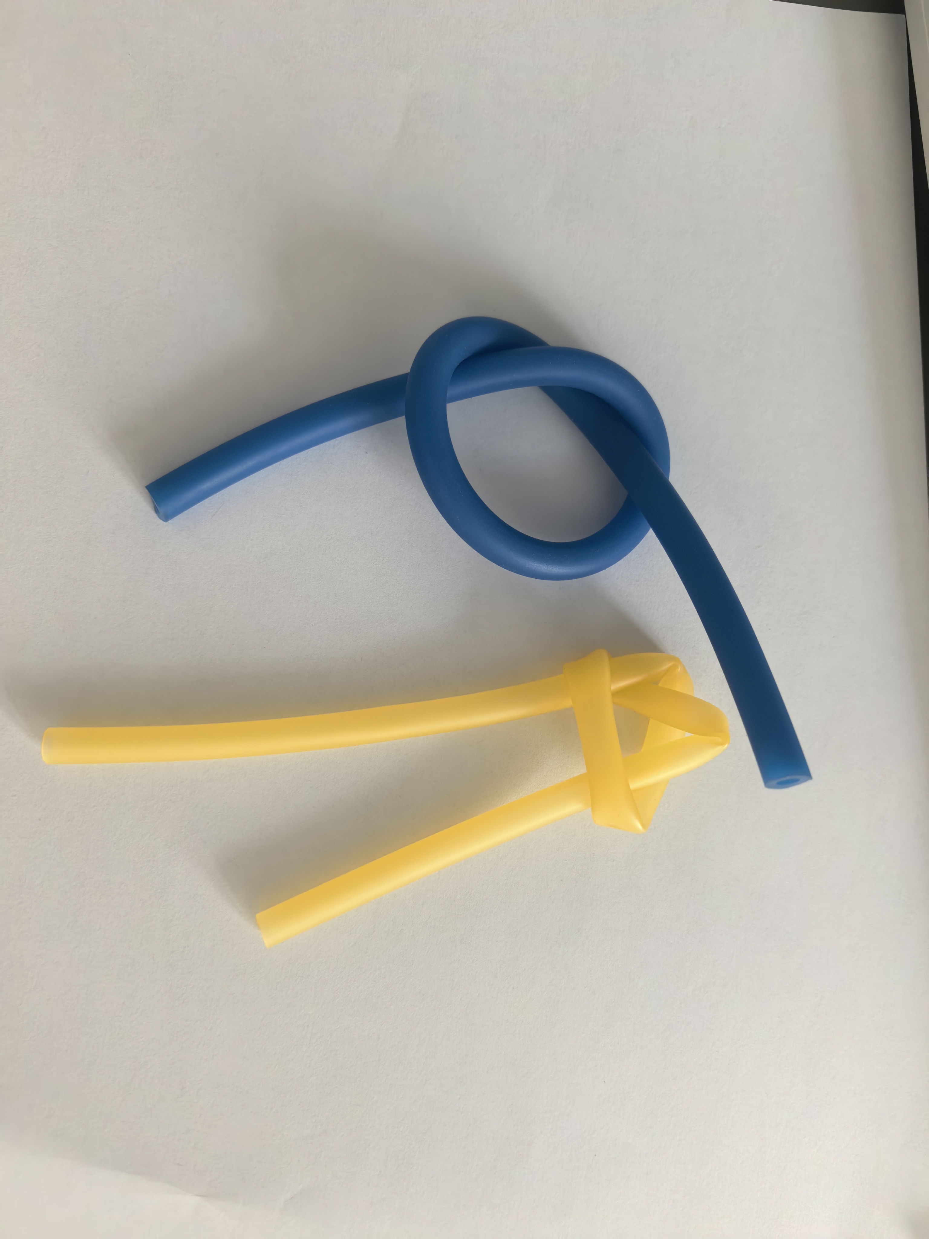 Yellow and blue hemostatic tubing knot samples on an inspection surface