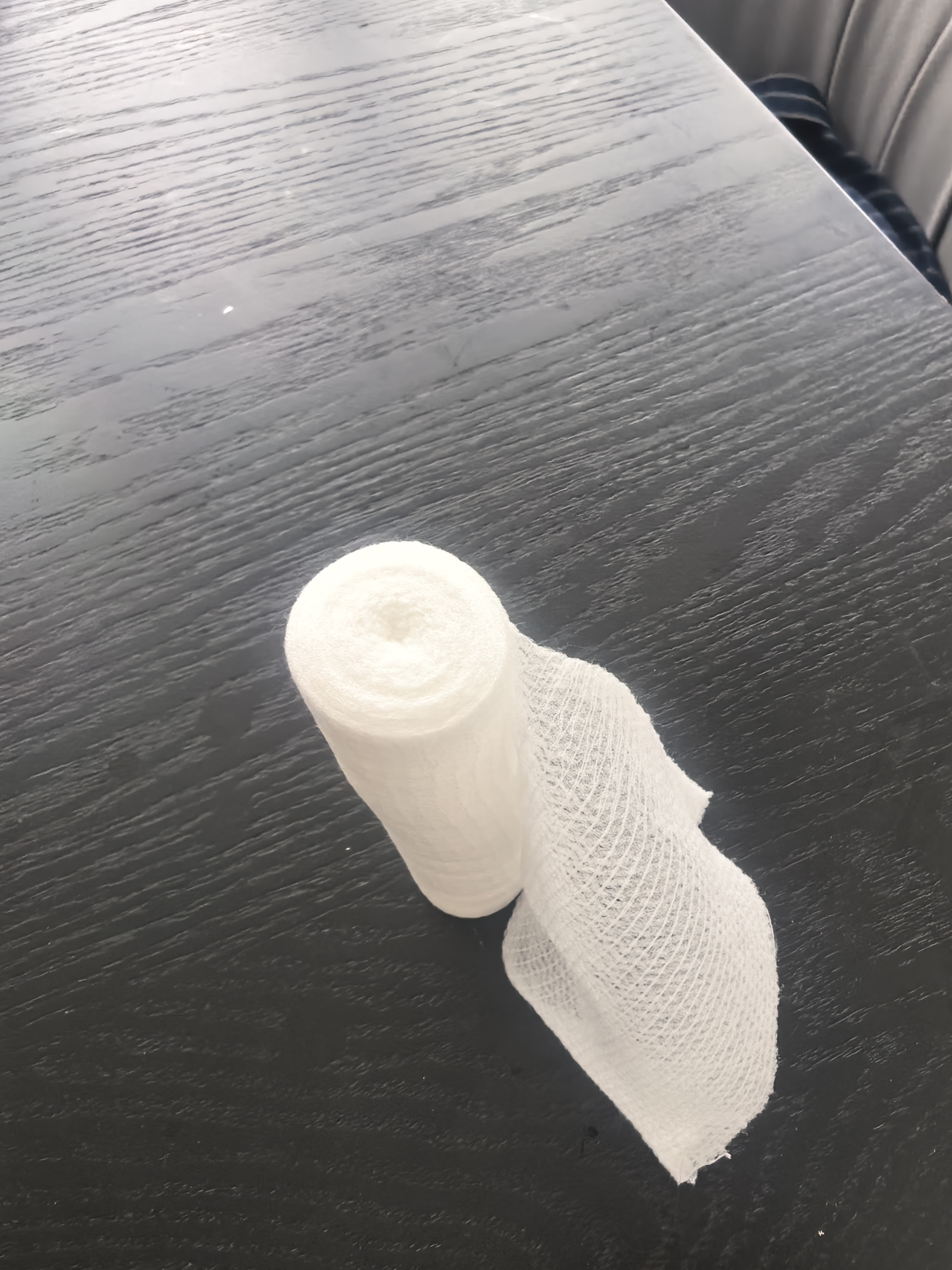White PBT bandage roll photographed on a dark inspection surface