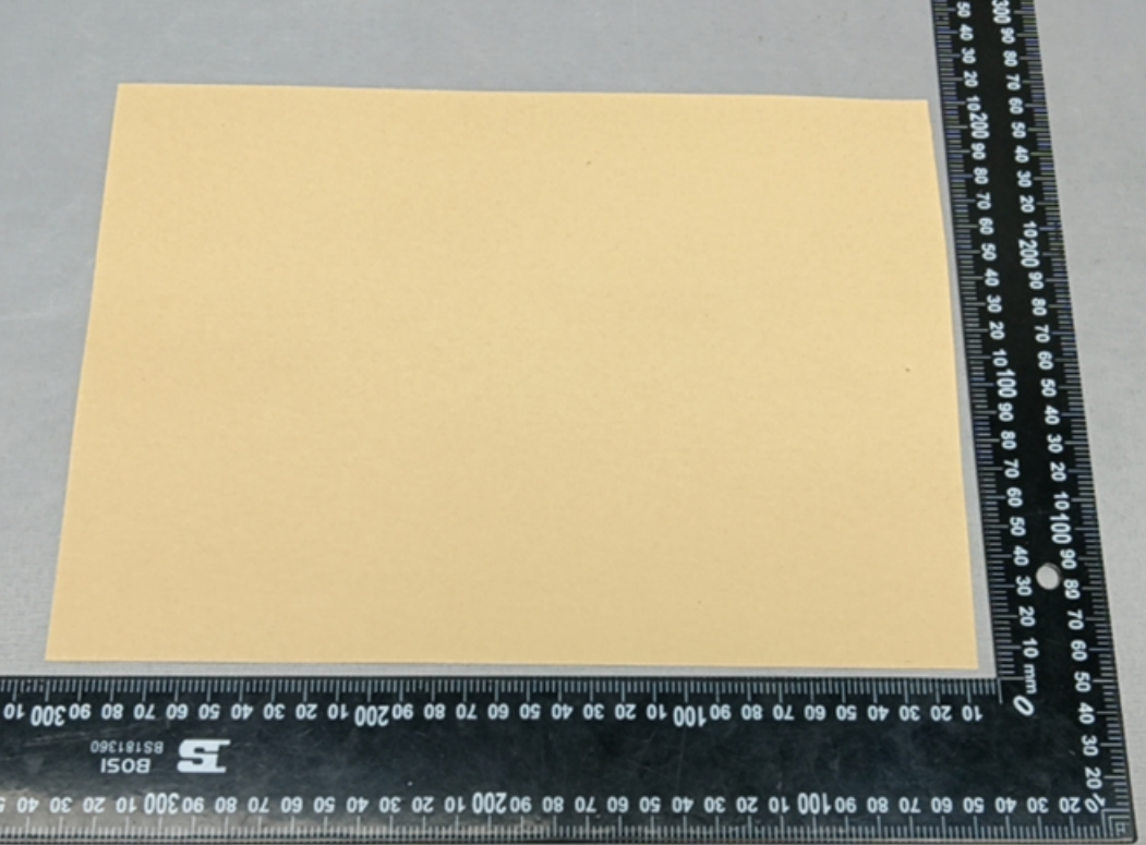 Red kraft paper sample sheet photographed beside a steel ruler