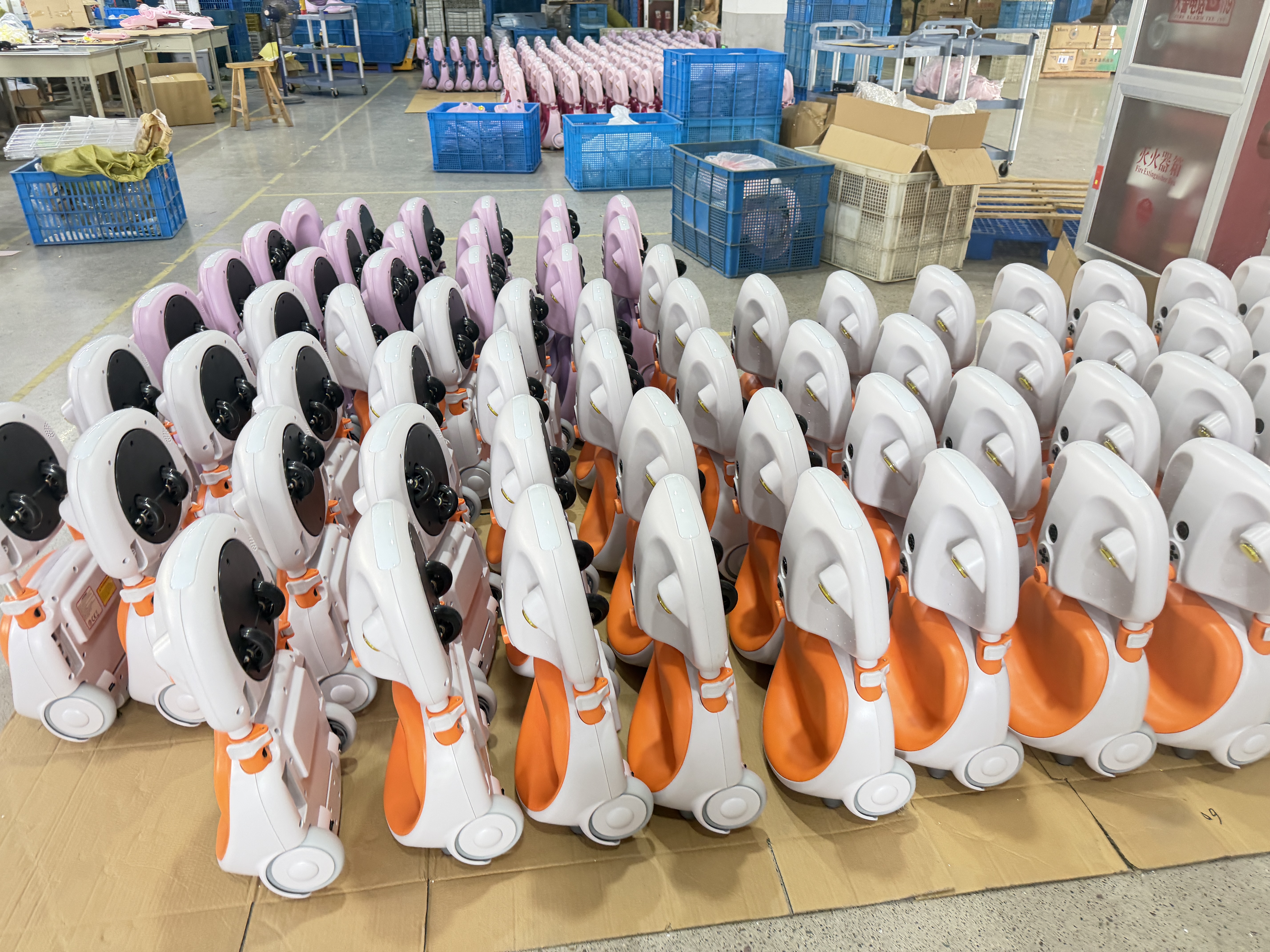 Rows of white, orange and pink child ride-on bodies near blue crates