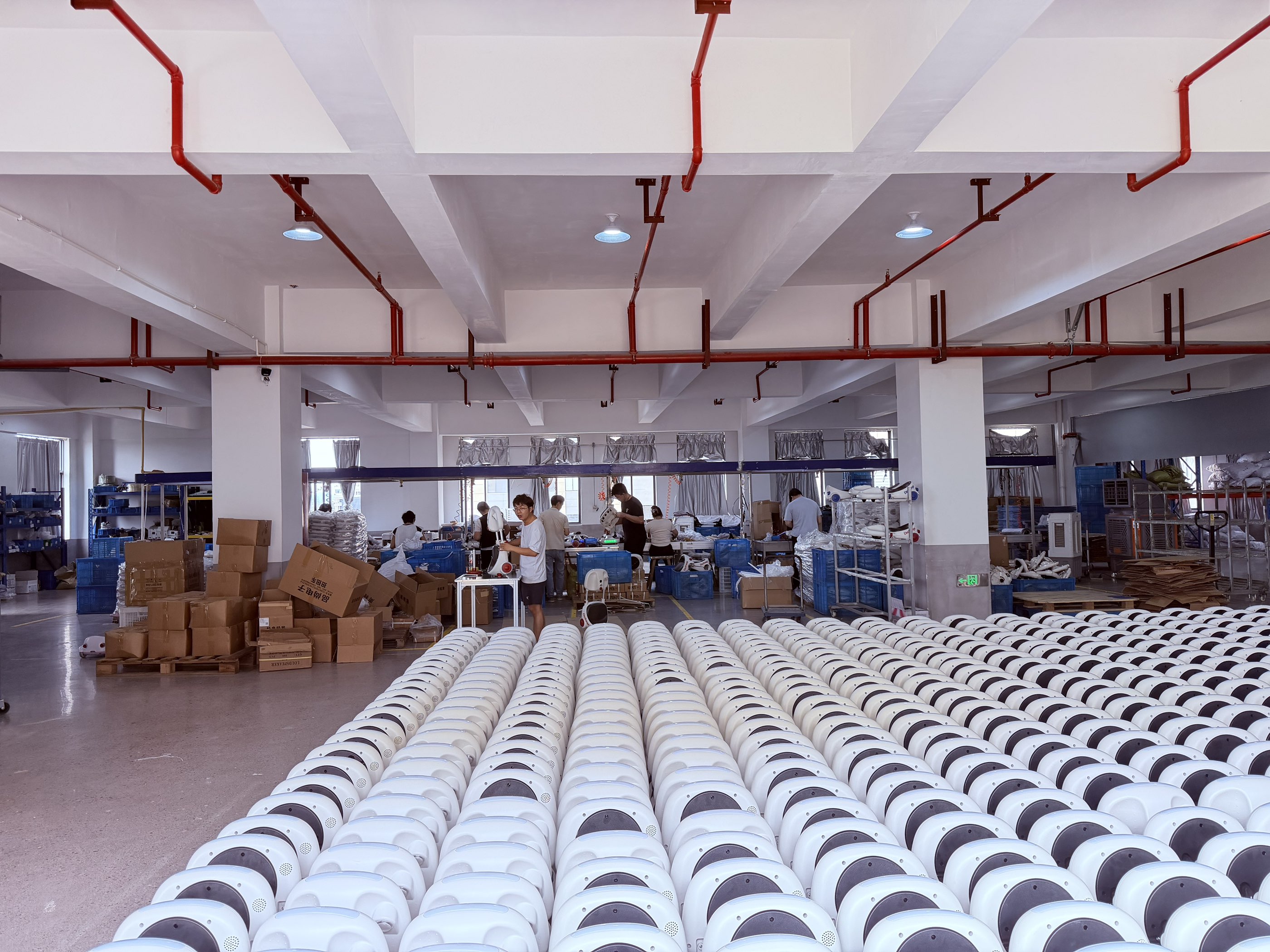 People in a workroom with rows of white ride-on bodies in the foreground