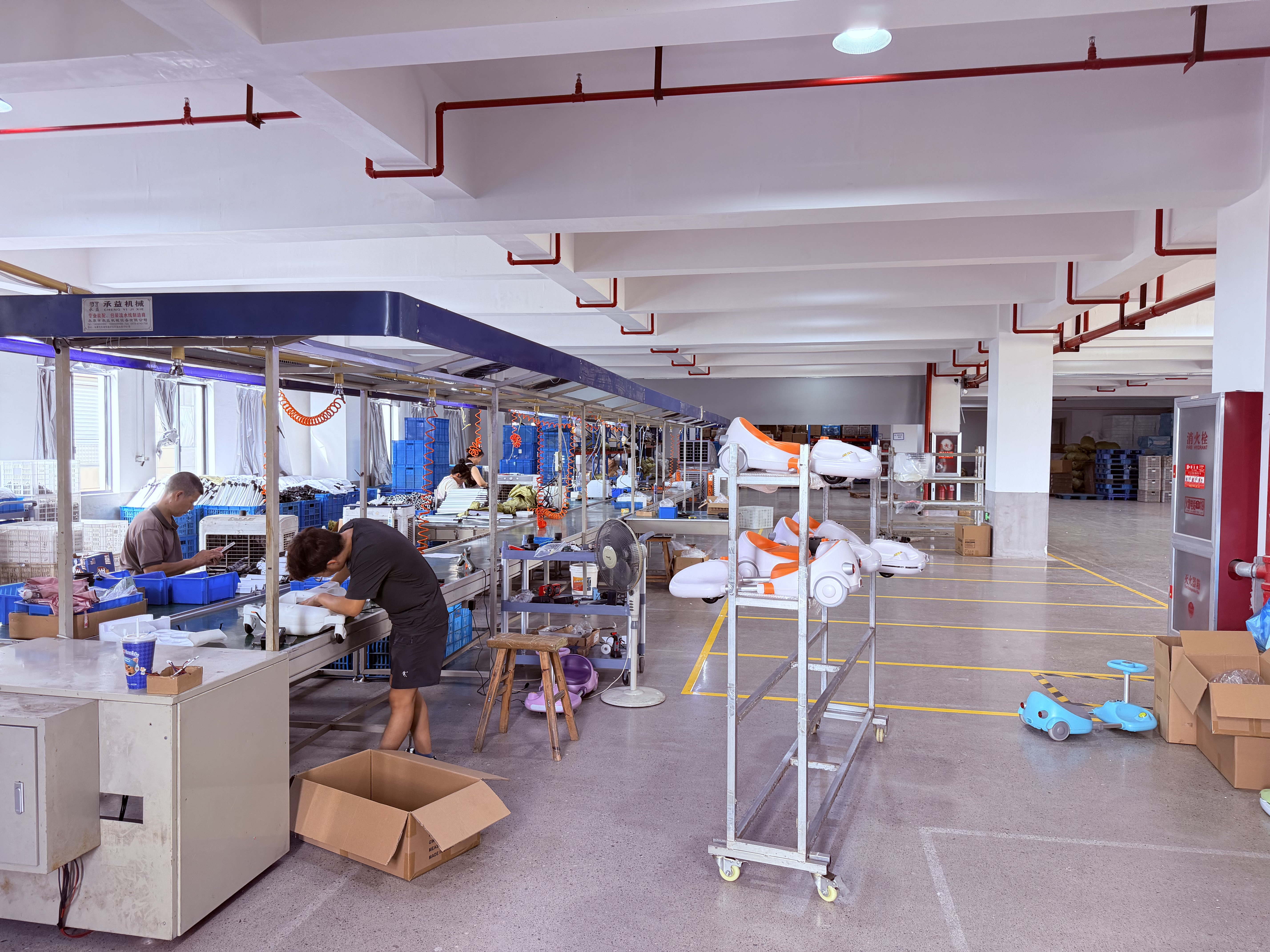 People at workbenches in a production room with parts and blue containers