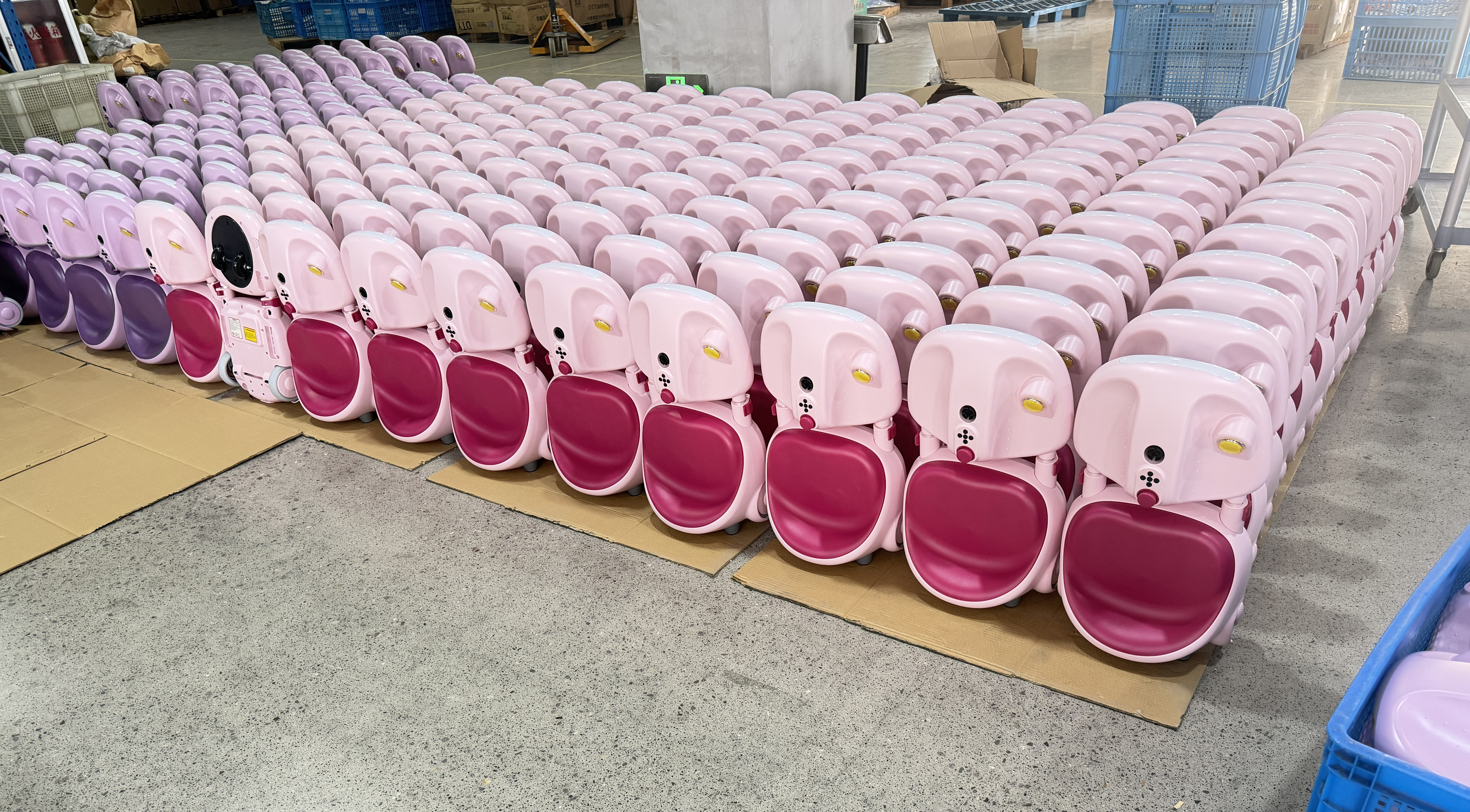 Rows of pink child ride-on vehicle bodies on the workroom floor
