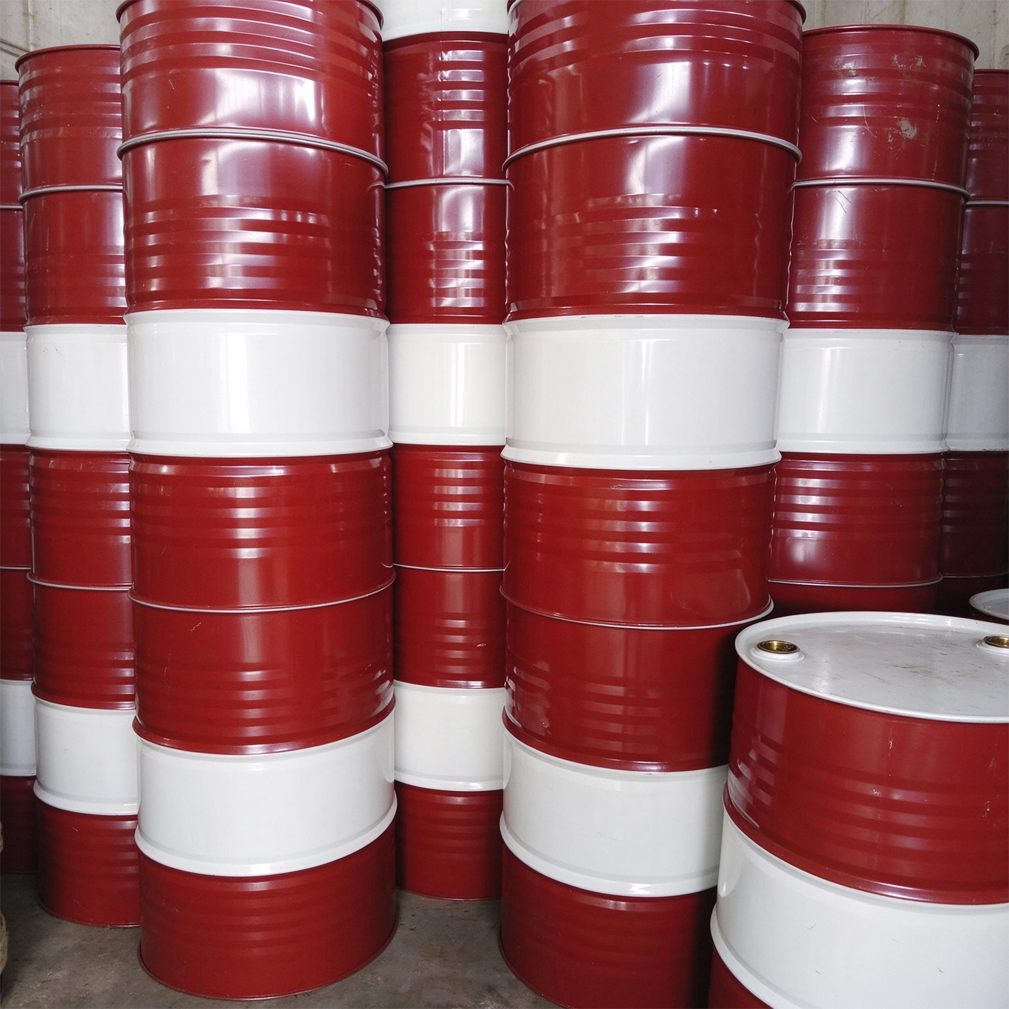 Stacked unbranded red and white steel drums, shown as generic packaging context.